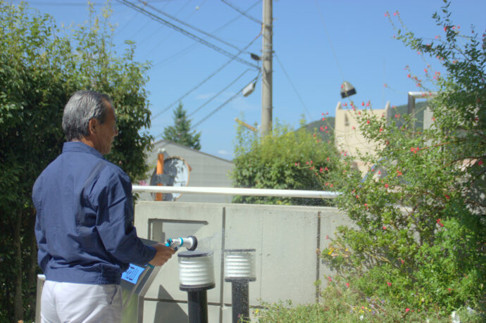 水を撒くマンション管理人