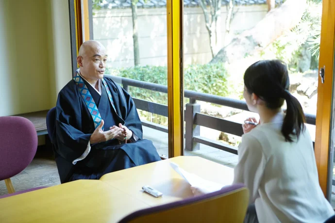 お寺の住職に取材をするライター