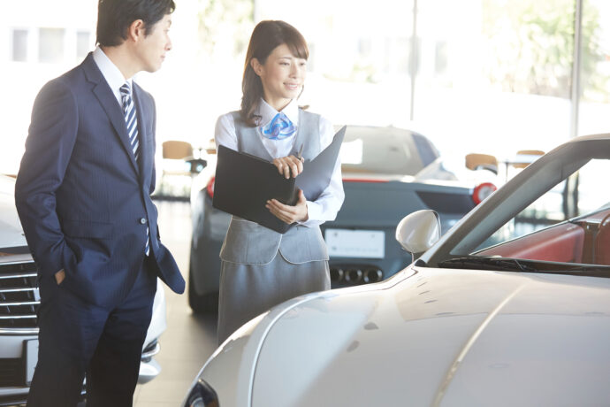 車の仕様を説明する自動車ディーラーに勤める女性