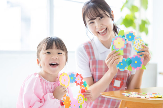 子どもと一緒に笑顔を向ける保育士