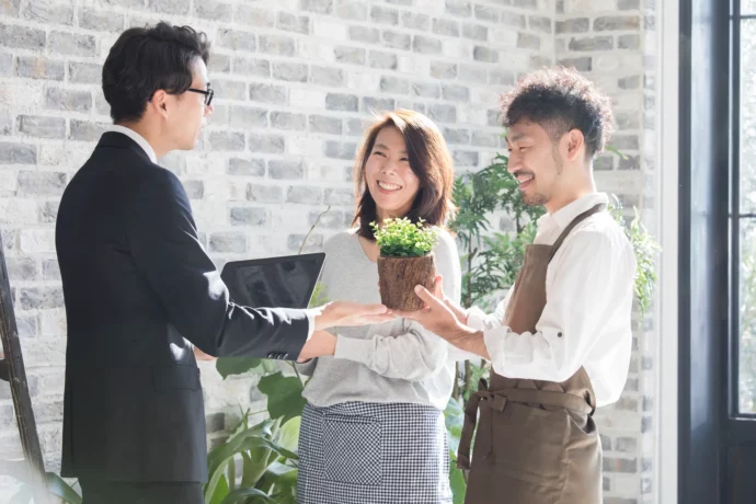 開店するお店に置く観葉植物についてアドバイスをするインテリアコーディネーターの男性