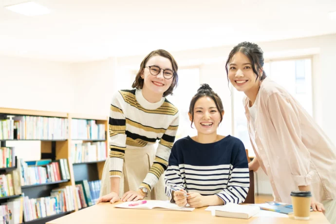 日本に留学し友人と図書館で勉強する外国人女性