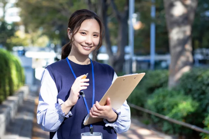 マーケティングリサーチの実践のために街中でインタビューを行う大学生