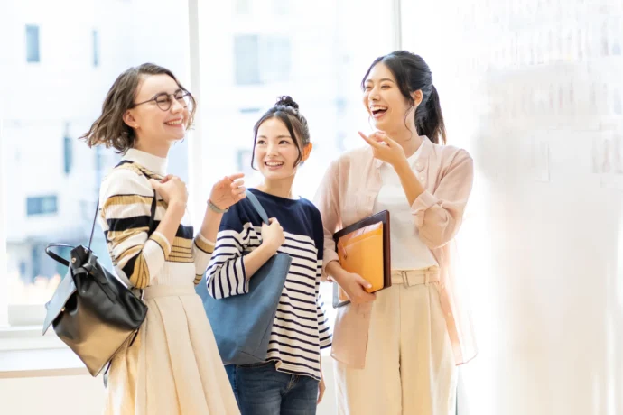 留学生を含む異なる文化的背景を持つ女子学生たちが明るい校舎内で楽しそうに会話する様子