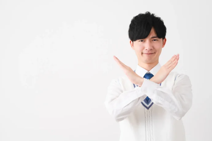 禁止のポーズをする男子生徒